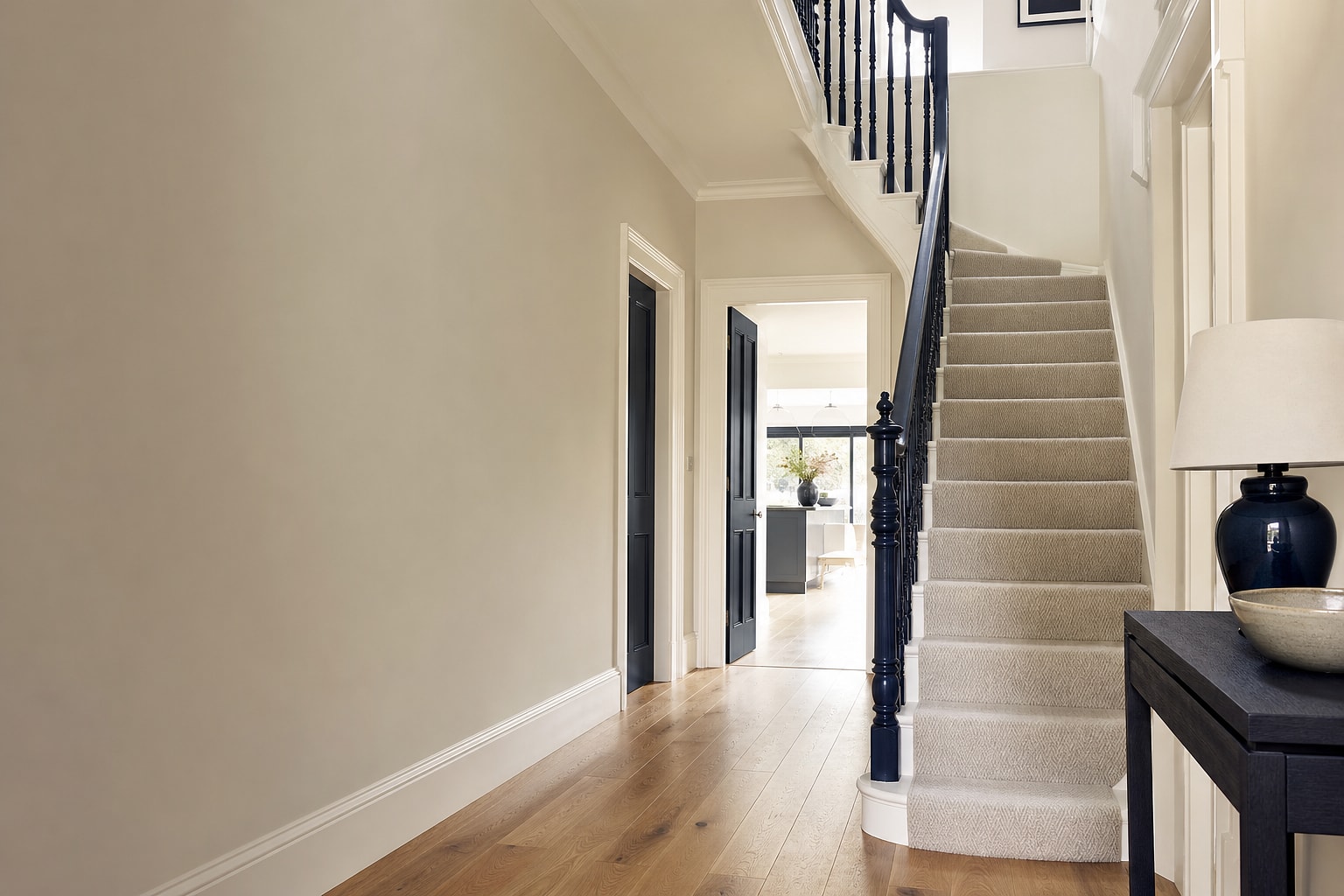 Elegant British hallway with a carpeted staircase, oak floor and dark-blue joinery
