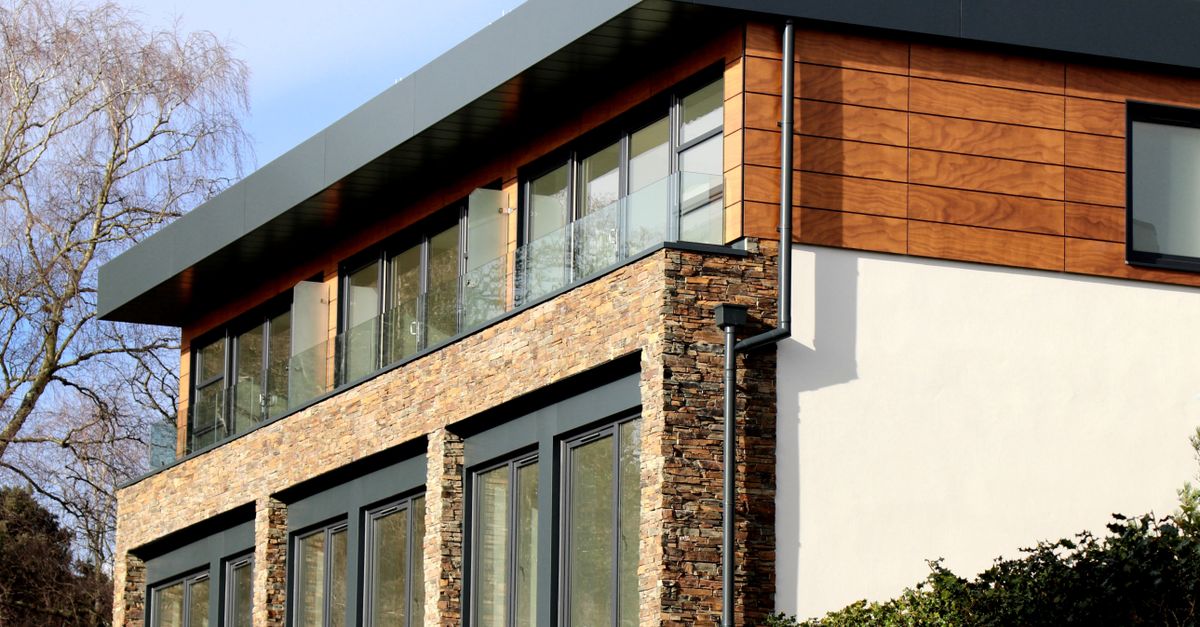 Contemporary house in Poole featuring a striking mix of stone and wood facade with large windows.